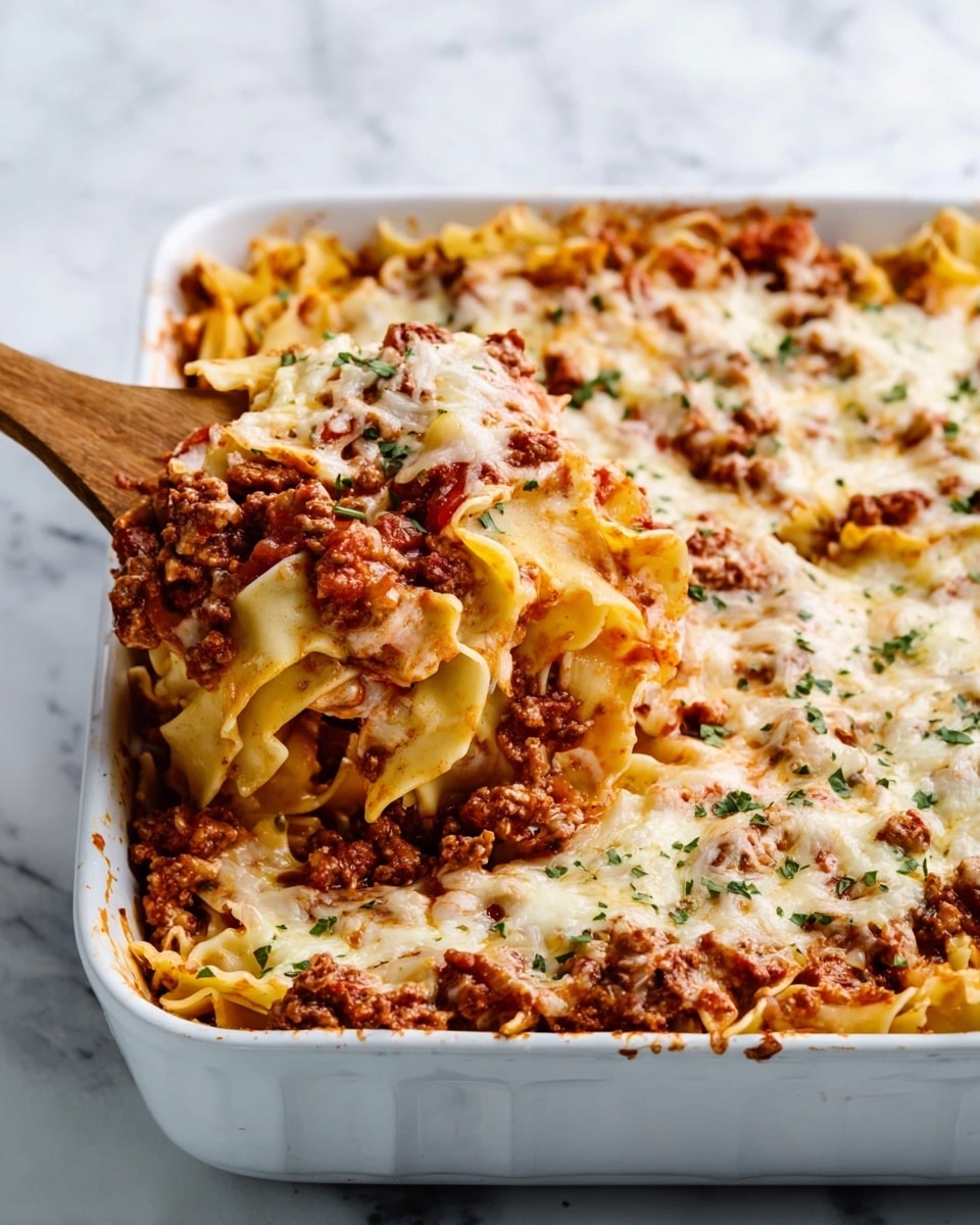 The image shows a large white rectangular baking dish filled with a layered pasta casserole. The bottom layer consists of wide, flat pasta noodles that are pale yellow. Above it is a thick layer of ground meat mixed with a rich red tomato sauce. On top, there is a generous layer of melted cheese that is creamy white in color with some golden brown spots. Small pieces of chopped green herbs are sprinkled over the cheese, adding a touch of color. A wooden spoon is lifting a portion of the casserole from the dish, showing the distinct layers clearly. The dish is set on a white marbled surface. Photo taken with an iphone --ar 4:5 --v 7