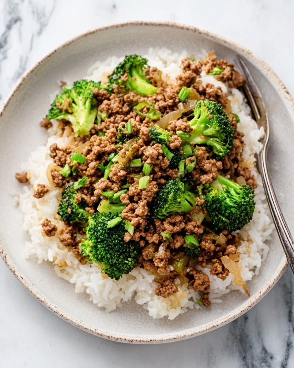 A white plate holds a dish with a base layer of white rice, topped with a thick layer of cooked ground meat mixed with small pieces of onions and bright green broccoli florets scattered on top. Each element shows clear texture: the rice looks soft and fluffy, the meat layer is crumbly and mixed with sautéed onions, and the broccoli adds a fresh, slightly rough texture. A silver fork rests on the edge of the plate, placed on a white marbled surface. Photo taken with an iphone --ar 4:5 --v 7