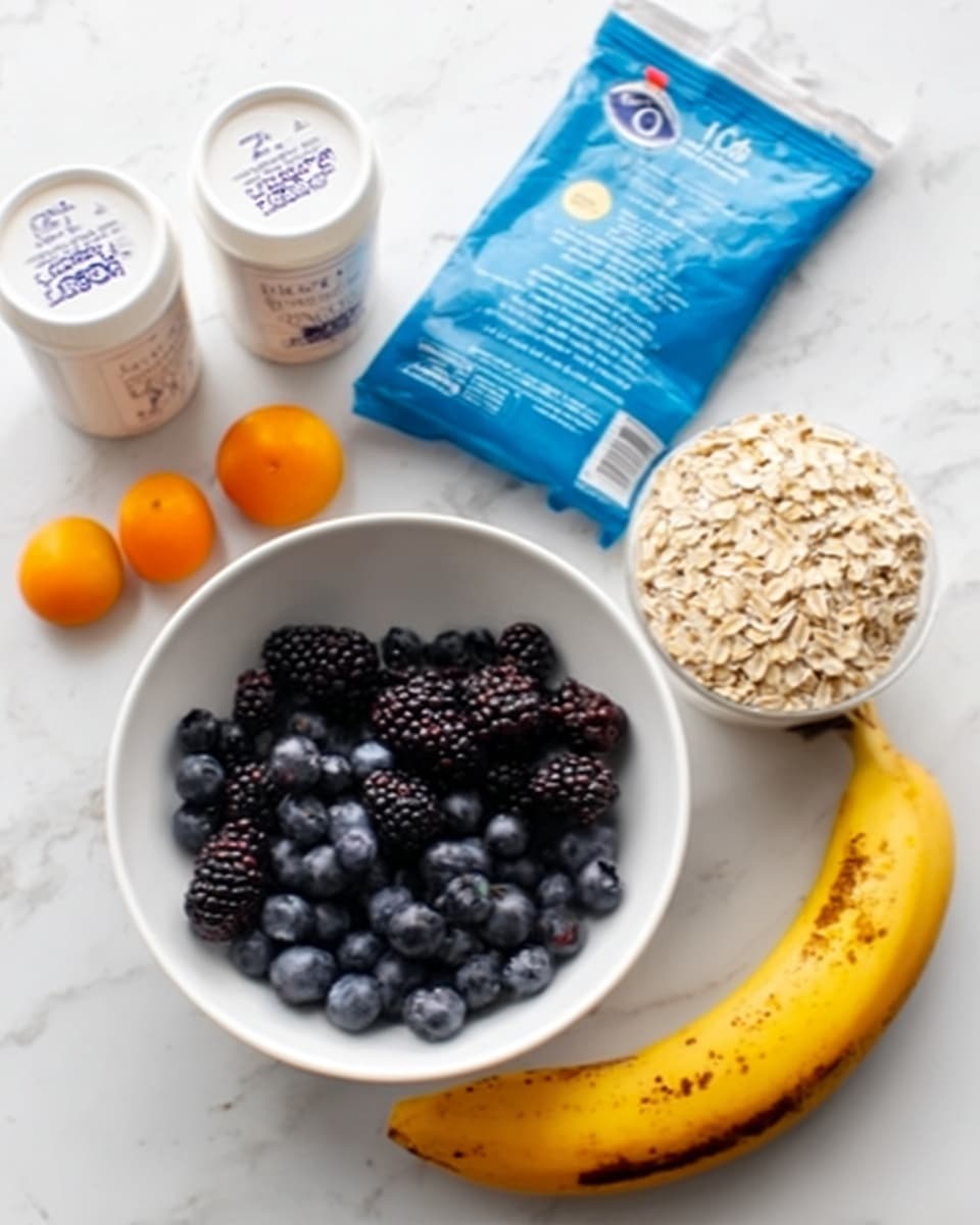 The image shows a white bowl filled with dark blueberries and blackberries placed on a white marbled surface. To the right of the bowl is a ripe yellow banana with brown spots. Above the bowl is a white measuring cup filled with light brown rolled oats. To the left of the bowl are two white yogurt containers with plain labels next to small orange fruits resembling kumquats. Behind all these items is a blue oatmeal packet standing upright. The photo taken with an iphone --ar 4:5 --v 7