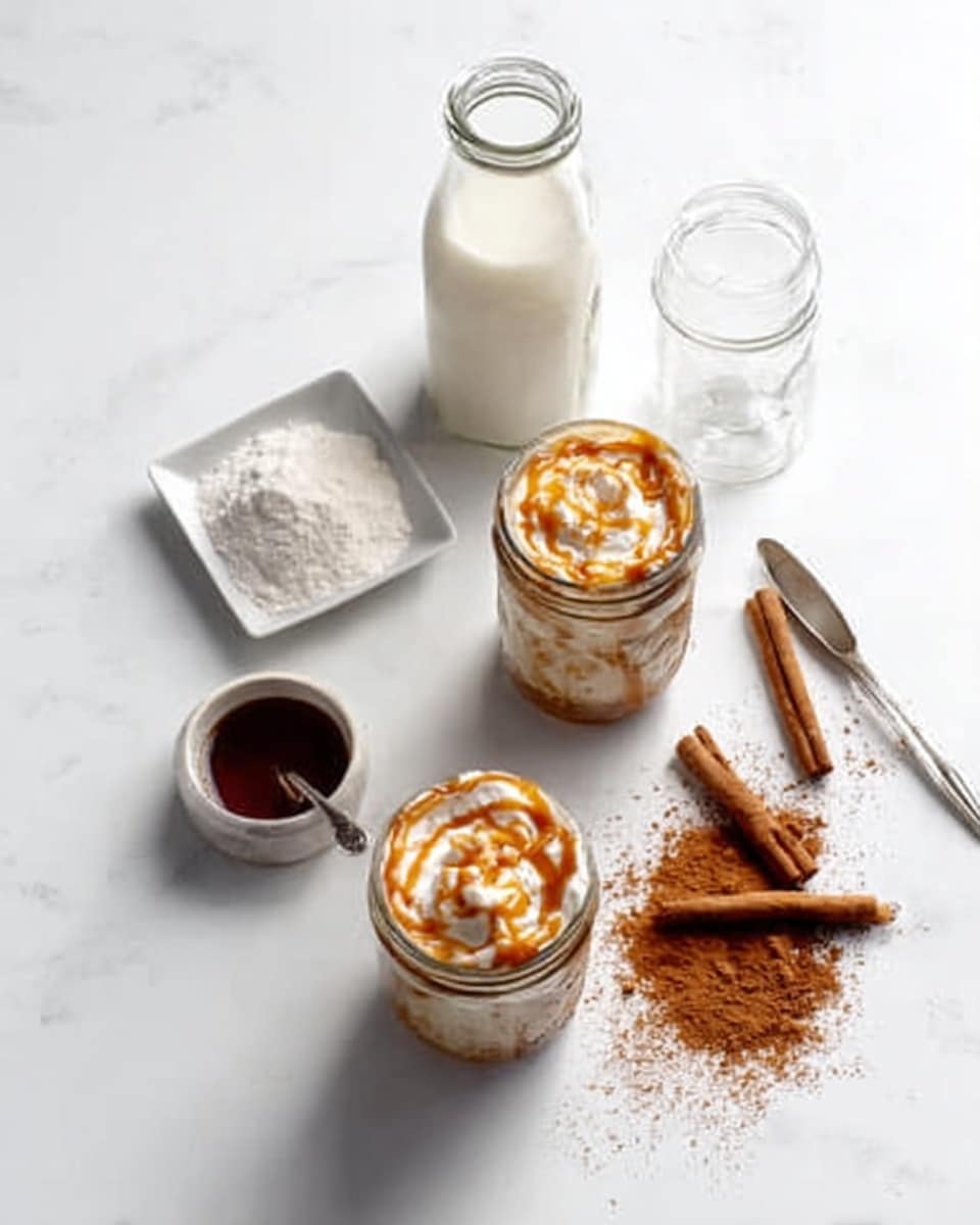 The image shows two white jars filled with a creamy drink topped with caramel drizzle, each jar placed on a white marbled surface with soft shadows. Around the jars, there are clear glass bottles — one tall and empty, the other with milk — standing upright. Nearby, a small white square dish holds a mound of white powdered sugar, while a white round bowl contains a cinnamon powder with a heart shape in the center, accompanied by two cinnamon sticks arranged diagonally beside it. A metal spoon with dark liquid rests next to the bowl, all placed neatly around the jars, captured from above in soft natural light. Photo taken with an iphone --ar 4:5 --v 7