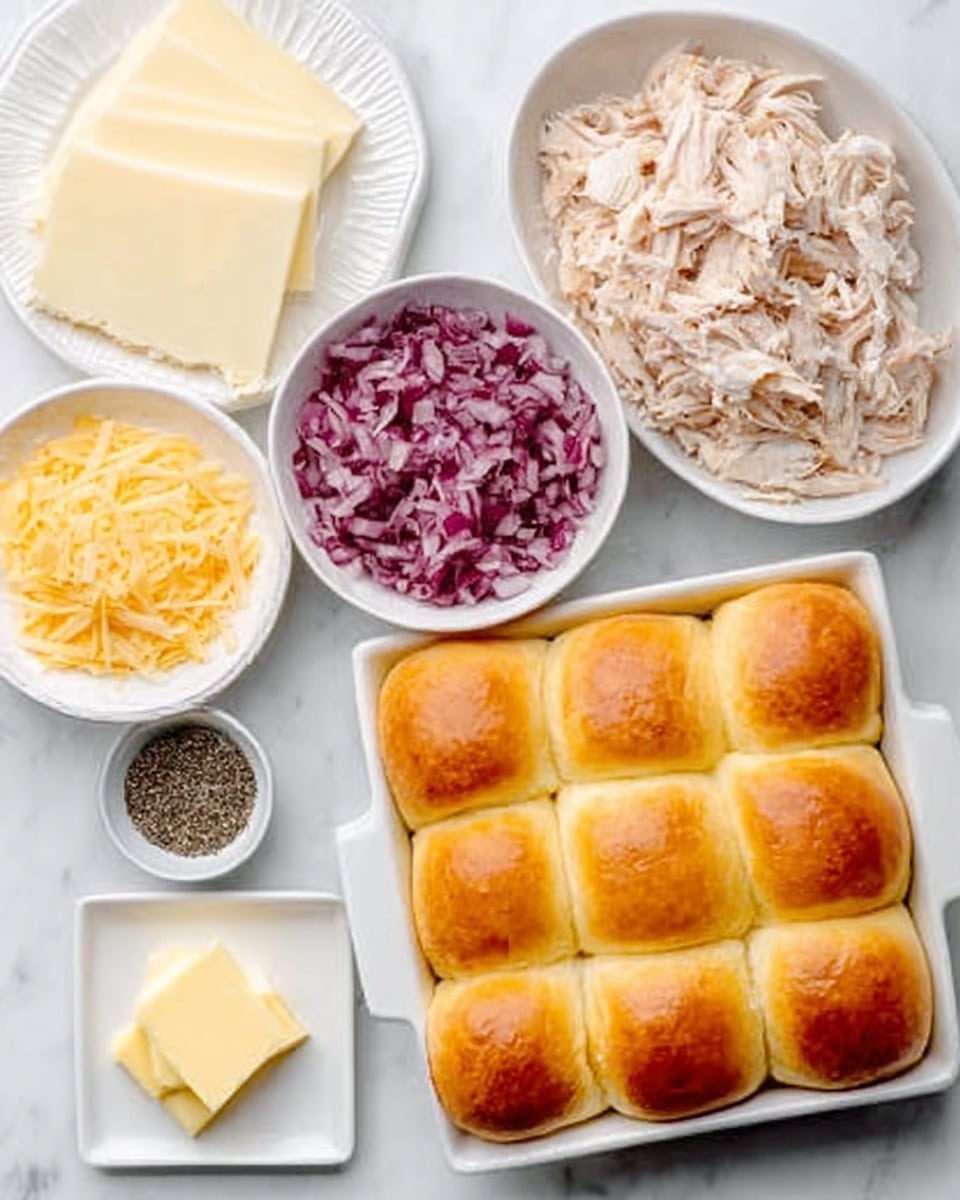 The image shows several white bowls and a white rectangular dish on a white marbled surface. The bottom right dish holds a layer of nine soft, golden brown dinner rolls arranged in a 3x3 grid. Above it to the right is a white bowl filled with shredded light brown and white chicken pieces. To the left of that is a white bowl filled with finely chopped red onions. Diagonally below this bowl is a small bowl with dark coarse pepper. Below the pepper is a small square plate with two slices of pale yellow butter. At the top left corner, there is a white plate with three thick slices of white cheese. The picture is clean and bright, with a woman's hand partly seen near the bowls. photo taken with an iphone --ar 4:5 --v 7