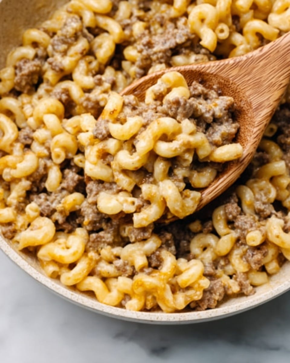 A close-up of a wooden spoon lifting a portion of cheesy pasta with ground meat from a white pot with a black rim. The pasta is curly macaroni, covered in melted yellow-orange cheese that stretches in thin strings down to the pot. The ground meat pieces are mixed evenly throughout the pasta, adding small brown bits among the creamy cheese and pasta. The background and surface are white marbled texture. Photo taken with an iphone --ar 4:5 --v 7