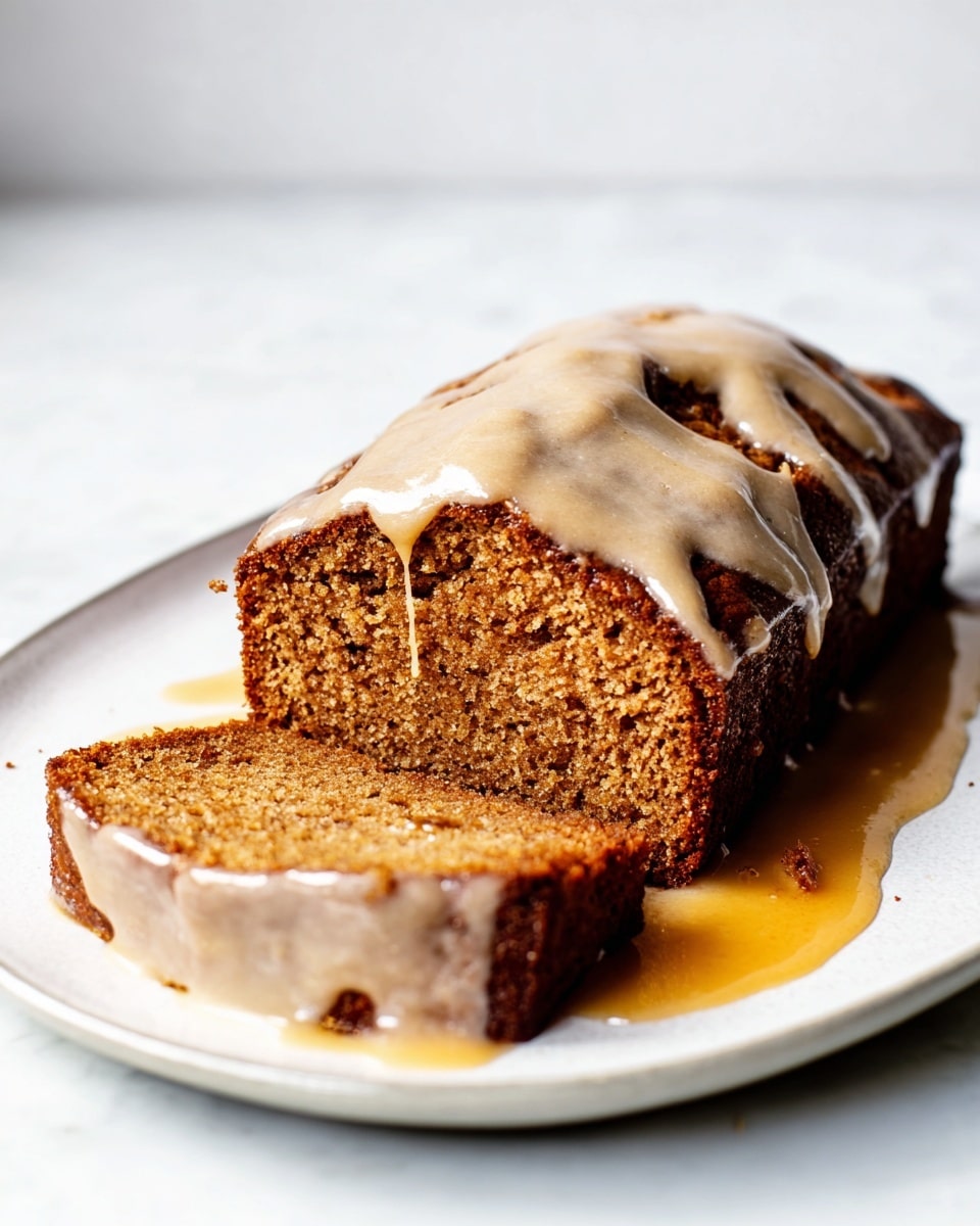 A rectangular slice of brown cake with a soft, moist texture is placed on a white plate. The cake has a rich orange-brown color and is topped with a smooth, light beige glaze that drips slightly down the sides, pooling around the base. One slice lies flat in front of the main piece, showing the dense crumb inside. The plate rests on a white marbled surface with a soft, blurred white background. photo taken with an iphone --ar 4:5 --v 7