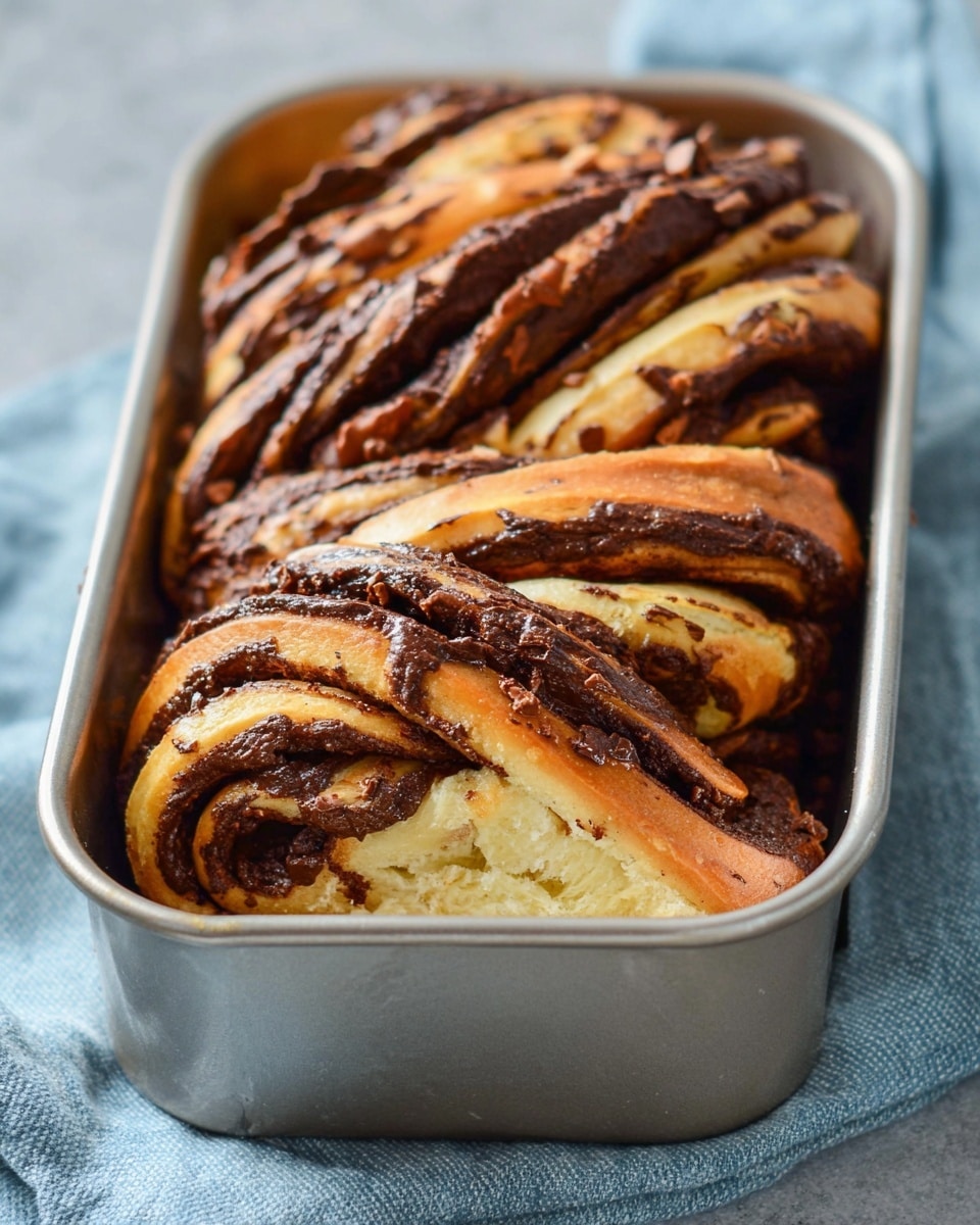 A rectangular piece of light beige dough is spread out flat on a white marbled surface dusted lightly with flour. The dough is covered evenly with a thick, dark brown, slightly glossy chocolate spread, leaving a thin border of plain dough visible around the edges. Two large male hands with visible veins and a silver ring on the left ring finger are seen gently rolling the dough from the top edge toward the center. The scene suggests the start of rolling up a chocolate-filled dough roll. photo taken with an iphone --ar 4:5 --v 7