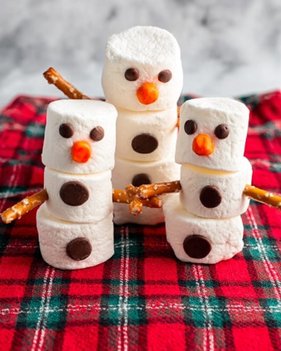 The image shows a mug filled with hot chocolate topped with a snowman made of three large white marshmallows stacked vertically. The snowman’s face has small black dots for eyes and mouth, an orange triangle for a nose, and two tiny black dots for buttons on the middle marshmallow. The snowman’s arms and legs are made of thin brown sticks placed on either side and below the marshmallow stack. The mug is white and sits on a shiny, warm copper-colored tray. Nearby, there is a white container filled with more large marshmallows and two white decorative trees. A bright red bow is placed behind the mug on a white marbled surface. photo taken with an iphone --ar 4:5 --v 7
