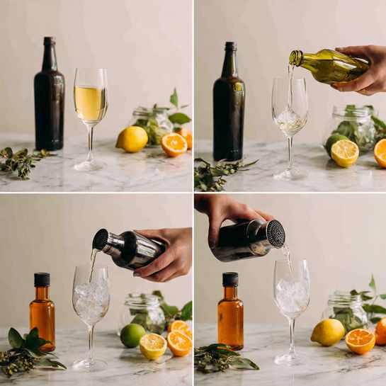 The image shows four steps of making a mixed drink on a white marbled surface. In step 1, a woman's hand pours a light brown liquid into a tall, clear glass surrounded by a small bottle of amber liquid, a lemon half, and a lime half, with a dark bottle in the back. Step 2 shows a black metal shaker with the glass upside down inside it, keeping the other items in the same place. Step 3 shows a woman's hand dropping ice cubes into the shaker, the bottle, lemon, and lime still in the background. In step 4, the shaken drink is poured from a black shaker through a strainer into a clear stemmed glass, with green leaves, a small bottle, and a jar with orange slices around it. photo taken with an iphone --ar 4:5 --v 7