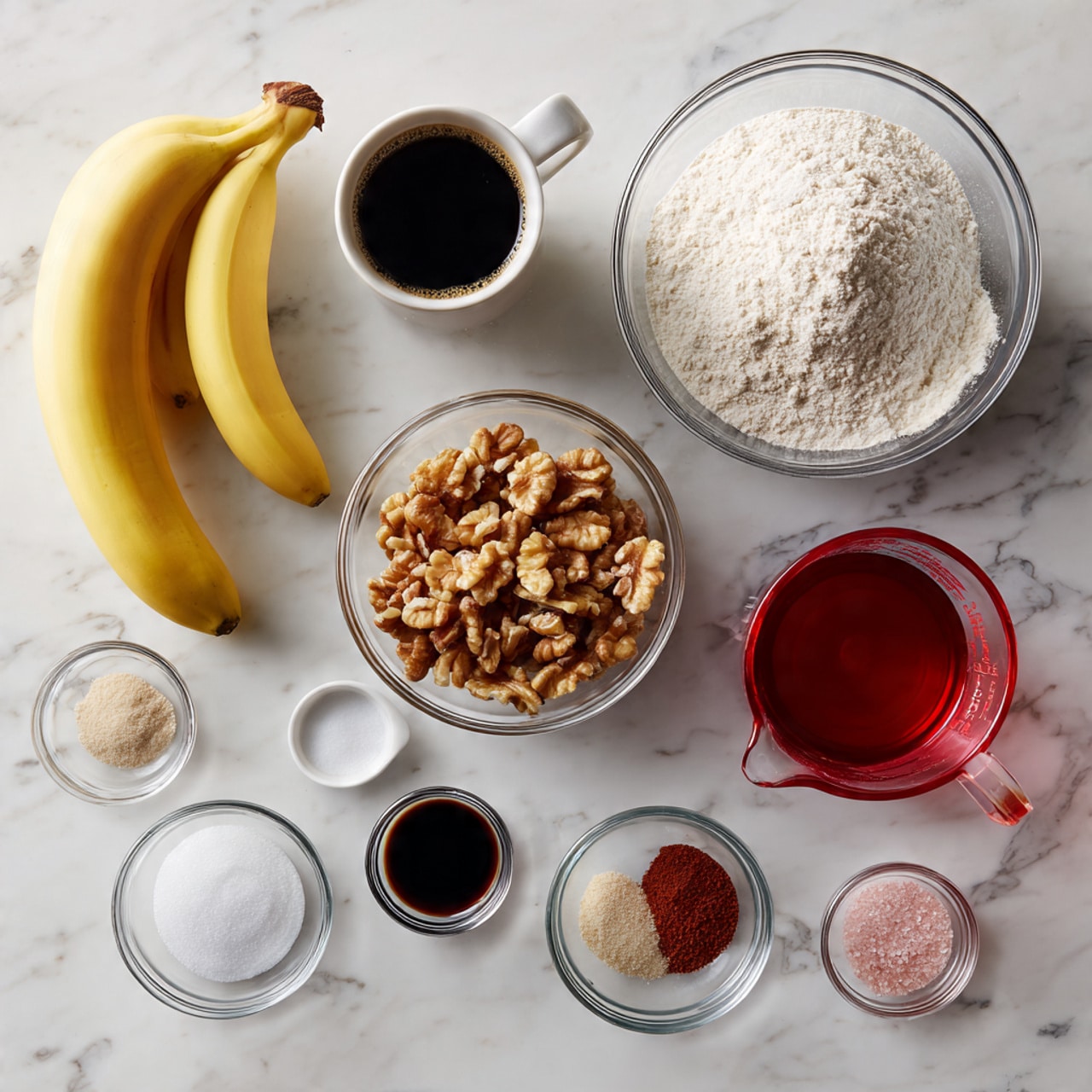 The image shows a white marbled surface with several clear glass containers holding different ingredients arranged neatly. In the back, there is a cup with black coffee, and a large glass bowl filled with light beige flour. In front, there are two bananas laying to the left. Clear glass bowls contain white granulated sugar, a dark brown liquid, a reddish liquid, small amounts of spices in two smaller bowls, and a medium bowl filled with chopped walnuts. The overall setup clearly shows each ingredient with simple colors and textures, all on a white marbled background. photo taken with an iphone --ar 4:5 --v 7