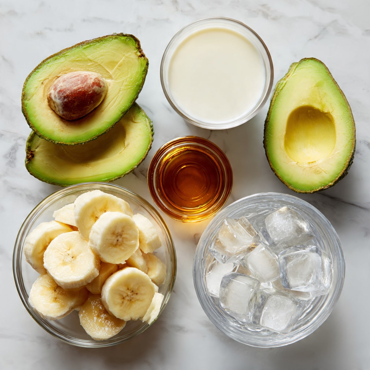 The image shows ingredients arranged on a white marbled surface. There are two avocado halves with green creamy flesh, a small glass bowl filled with sliced bananas that are pale yellow, a glass of white milk, a small glass container with brown liquid honey, and a clear bowl filled with large ice cubes. The colors are soft and natural with a clean, simple look. Photo taken with an iphone --ar 4:5 --v 7