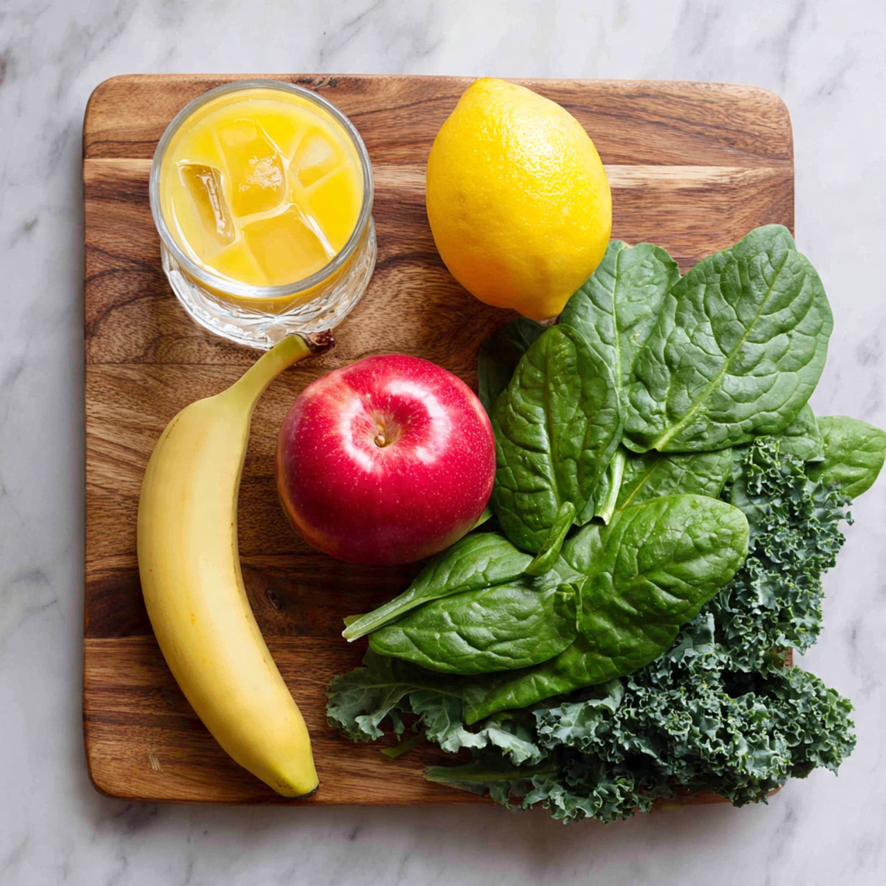 A wooden cutting board is placed on a white marbled surface, holding a colorful arrangement of fresh ingredients in a top-down view. On the left side, there is a glass filled with ice water sitting beside a clear glass cup filled with orange juice. Towards the top center, a whole bright yellow lemon and a shiny red apple are next to a peeled banana that curves gently to the right. The right side is densely covered with two kinds of leafy greens: large, smooth spinach leaves stacked above a layer of curly kale with its textured dark green leaves spreading toward the bottom of the board. The composition is well balanced with fresh colors and textures. photo taken with an iphone --ar 4:5 --v 7
