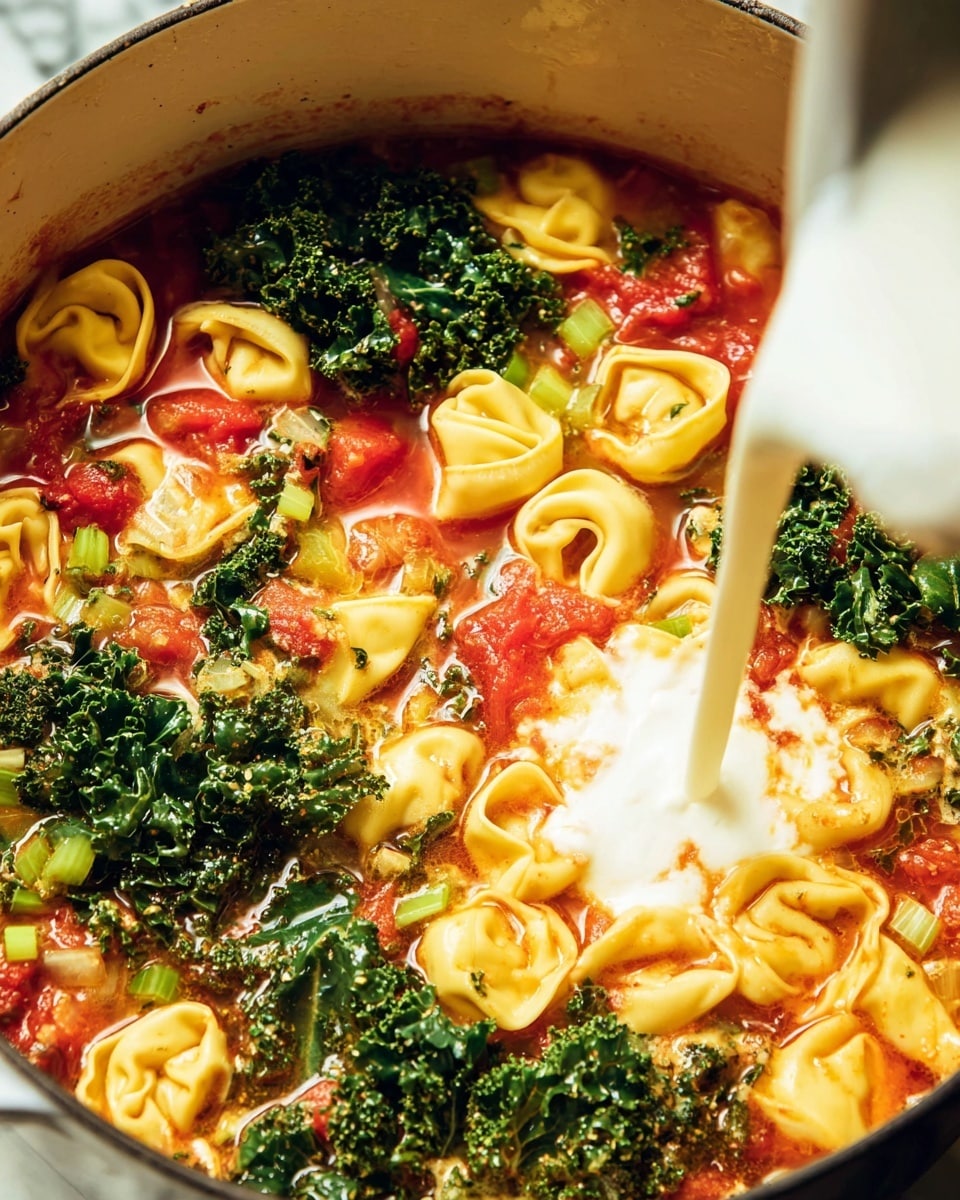 A close-up image of a pot filled with a colorful soup showing three main layers: the first layer is a red tomato-based broth with small pieces of green celery and red tomato chunks scattered throughout, the second layer has yellow tortellini pasta floating evenly on top, and the third layer features deep green curly kale leaves spread across the surface. A creamy white sauce is being poured from the top right corner into the soup, blending softly with the vibrant colors below. The pot is set on a white marbled surface. photo taken with an iphone --ar 4:5 --v 7