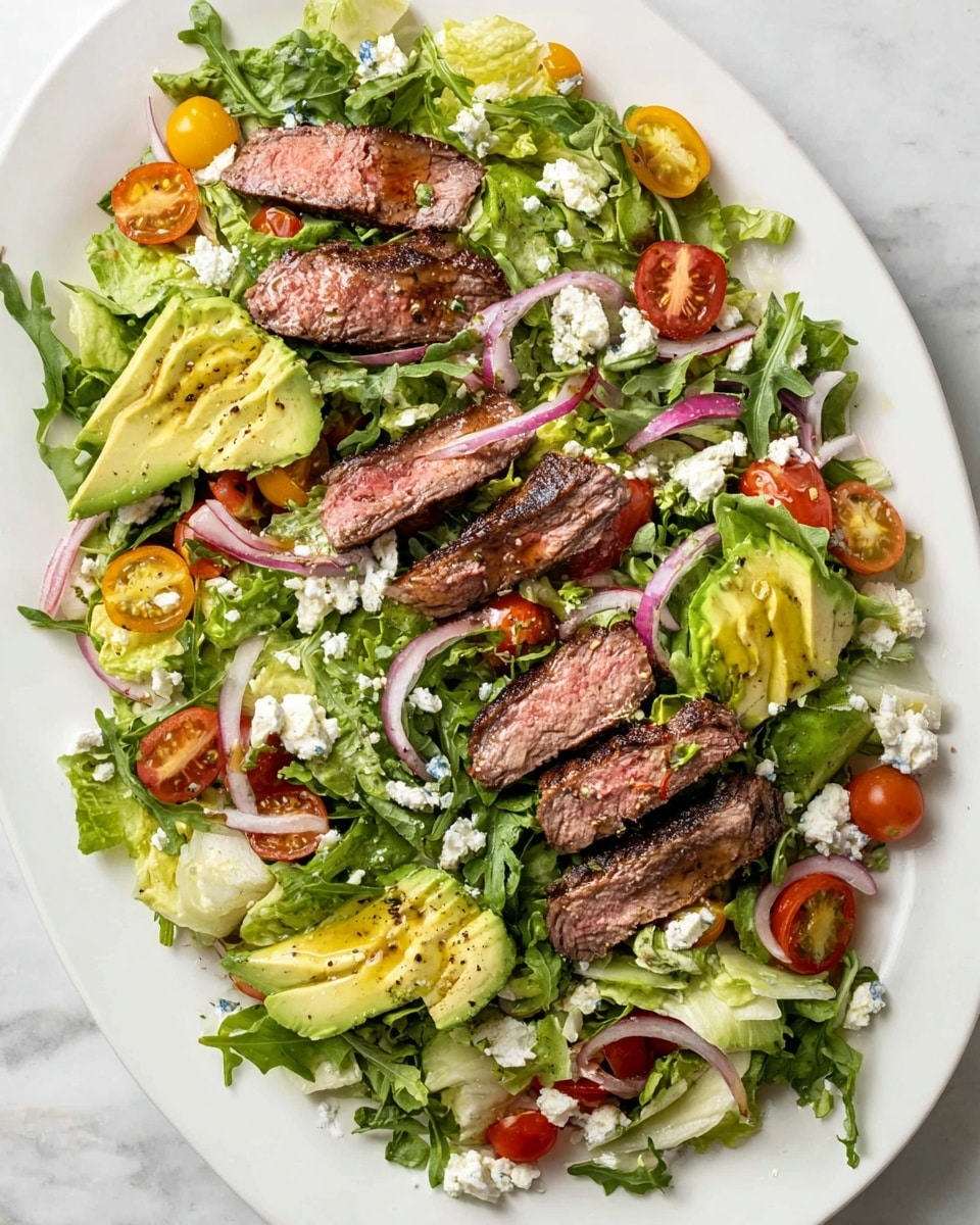 A large white oval plate holds a fresh salad with several layers: the base layer is a mix of green leafy arugula and pale yellow lettuce spread evenly across the plate. On top, there are slices of medium-cooked steak, showing a light pink center with charred brown edges, placed in small clusters around the plate. Bright green avocado halves are sliced and positioned near the steak, with a drizzle of olive oil and a sprinkle of black pepper. Scattered among these are halves of red and yellow cherry tomatoes, adding pops of color. Thinly sliced red onion rings and crumbled white cheese are sprinkled throughout the salad. The plate sits on a white marbled surface, creating a clean and fresh background. Photo taken with an iphone --ar 4:5 --v 7