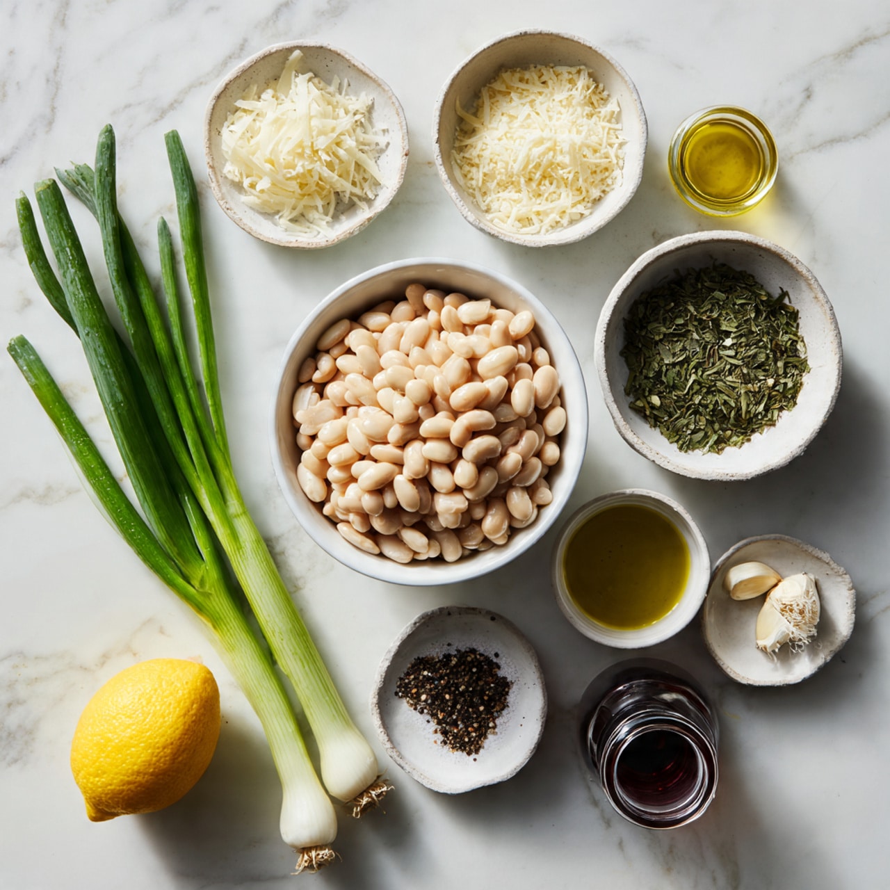 A top-down view shows a group of fresh ingredients for cooking arranged on a white marbled surface. In the center, there is a white bowl filled with pale beige white beans. Surrounding the bowl, clockwise from top left, are three green onions with long green tops, a small white bowl with dried green herbs, a white bowl with grated white cheese, a small glass container with olive oil, a small jar with a dark brown liquid, a small white bowl with minced garlic, and a small white bowl with black pepper and salt. A whole yellow lemon sits at the bottom left. The lighting is soft, showing texture and natural color differences. Photo taken with an iphone --ar 4:5 --v 7