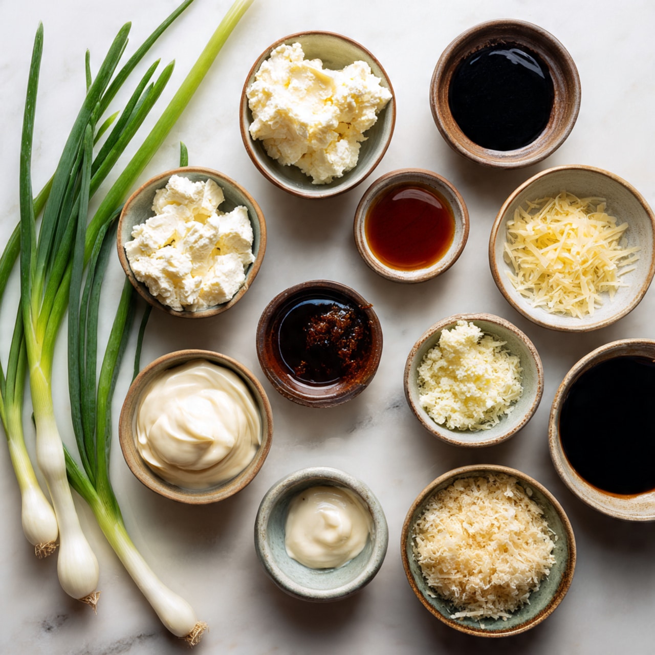This image shows an arrangement of small bowls and fresh green onions on a white marbled surface. There are three green onions with white tips on the left side. Eleven small bowls are spread across the surface; five light-colored bowls and six dark-colored bowls. The light-colored bowls hold creamy white thick cheese and light brown sauce. The dark-colored bowls contain a white creamy dollop, dark soy-like liquid, reddish-brown sauce, and black soy-like liquid. The other bowls contain shredded pale yellow cheese and a crumbly light beige textured ingredient. The bowls and ingredients are neatly placed, showing a variety of textures and colors ranging from white and pale yellow to dark browns and blacks. photo taken with an iphone --ar 4:5 --v 7