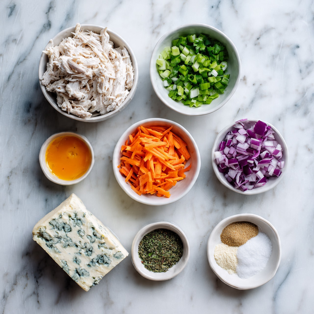 The image shows a white marbled surface with several white bowls and a block of blue cheese placed on it. There are five white bowls in total: one holding creamy white shredded chicken, a small bowl with bright orange sauce, a bowl with finely chopped green herbs, another with a mix of finely chopped purple onions, orange carrots, and green celery, and a small bowl containing a mix of dry ingredients including a dark green powder, white granules, and a light beige powder. The block of blue cheese sits on the surface near the bowls. The colors in the bowls create a bright and fresh contrast against the white marbled background. photo taken with an iphone --ar 4:5 --v 7