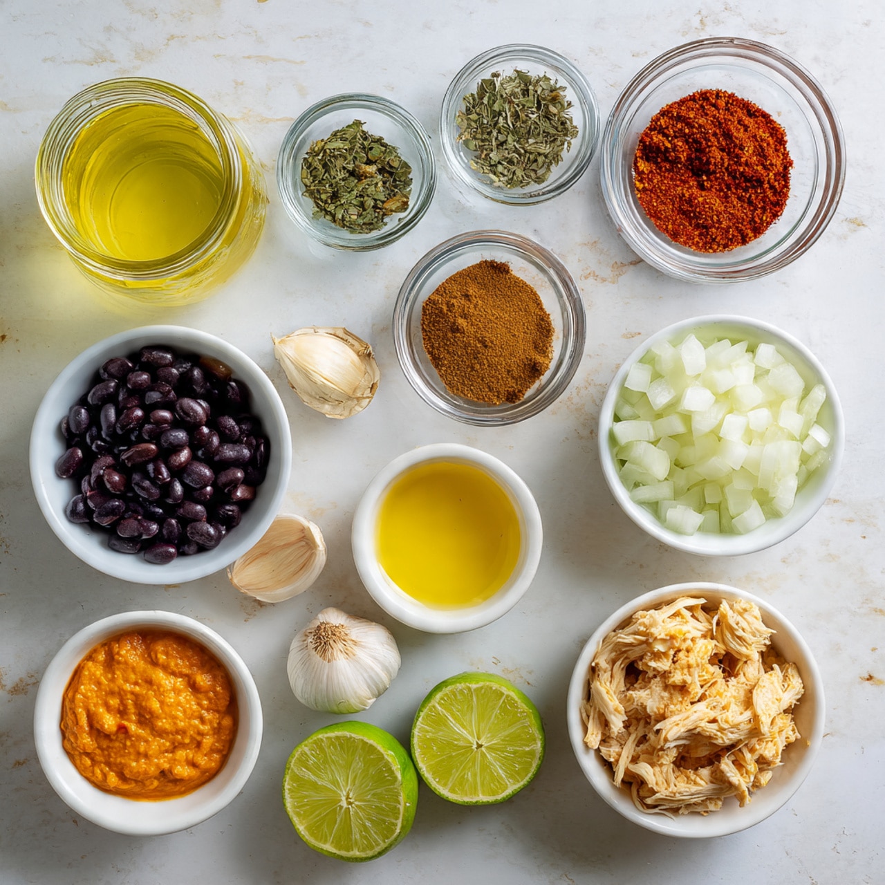 In the image, there are several small white bowls and one glass jar neatly placed on a white marbled surface. Starting from the top left corner, there is a glass jar filled with light yellow liquid. Next to it, a small clear bowl holds dried green herbs. To the right, another small clear bowl contains red spice powder. Below, there is a clear bowl with brown spice powder. In the center, a white bowl is filled with shiny black beans. To the right, a clear bowl holds chopped white onions. Moving down, a white bowl is filled with shredded light beige meat, likely chicken. Above that, a small clear bowl holds a light yellow liquid, possibly oil. On the left, a white bowl contains smooth orange paste. Below that are two halves of a lime with a bright green color. At the bottom left, a white bowl holds chunky tomato and green pepper mix. Between the bowls of black beans and orange paste, there are two garlic cloves. The neat arrangement and clean background highlight each ingredient's color and texture clearly. photo taken with an iphone --ar 4:5 --v 7