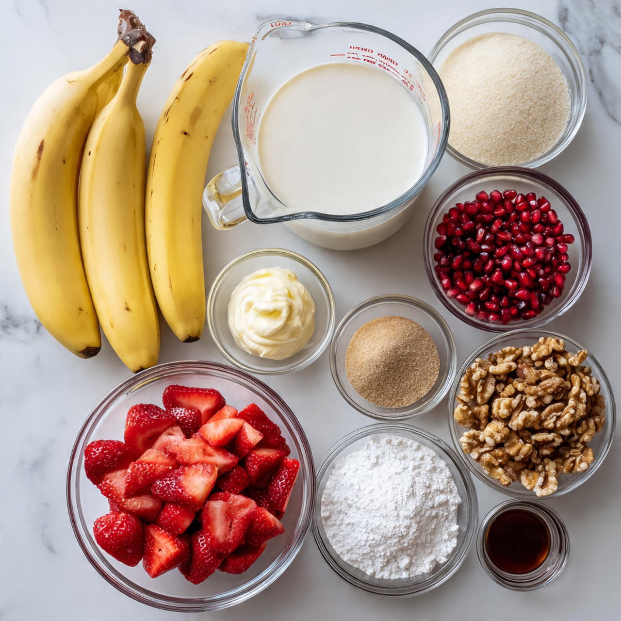 The image shows a white marble surface with ingredients arranged neatly. There are three whole yellow bananas on the left next to a clear glass measuring cup filled with white milk. In the center, a clear bowl is filled with bright red sliced strawberries, surrounded by smaller clear bowls containing red pomegranate seeds, brown sugar, white flour, creamy yellow softened butter, white sour cream, and white powdered sugar. To the right, there is a small glass with white sugar, a small cup with dark brown liquid vanilla extract, and a pile of chopped brown walnuts. All items are separate and placed in a clean, organized manner. Photo taken with an iphone --ar 4:5 --v 7