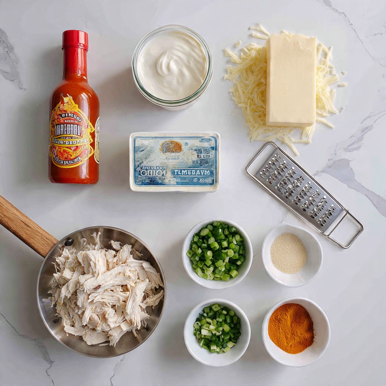 A flat lay image shows ingredients for a creamy chicken dish arranged neatly on a white marbled surface. On the top left is a bottle of bright red buffalo wing sauce with orange and yellow label colors. Next to it in the center is a round white container of sour cream with a red label and spoon image. On the top right is a rectangular block of pale yellow cheese with some freshly grated cheese pieces nearby and a metal grater at the edge. Below these items and centered is a rectangular package of cream cheese in white and blue packaging. On the bottom left, a small metal pan with a wooden handle holds shredded white chicken. To the right of it are three small white bowls arranged vertically—one with chopped green onions, another with chopped fresh green herbs, and the last one at the bottom with orange spice powder. Below the bowls there is another small white bowl filled with light beige garlic powder. The colors are a mix of whites, greens, reds, and yellows, with textures ranging from shredded chicken to smooth cream and rough toppings. Photo taken with an iphone --ar 4:5 --v 7