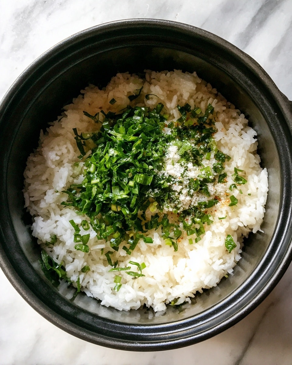Inside a black pot, there is one layer of white cooked rice, soft and fluffy. On top of the rice, there is a pile of finely chopped fresh green herbs with a few flakes of coarse salt scattered over the herbs. The pot is set against a white marbled surface. Photo taken with an iphone --ar 4:5 --v 7