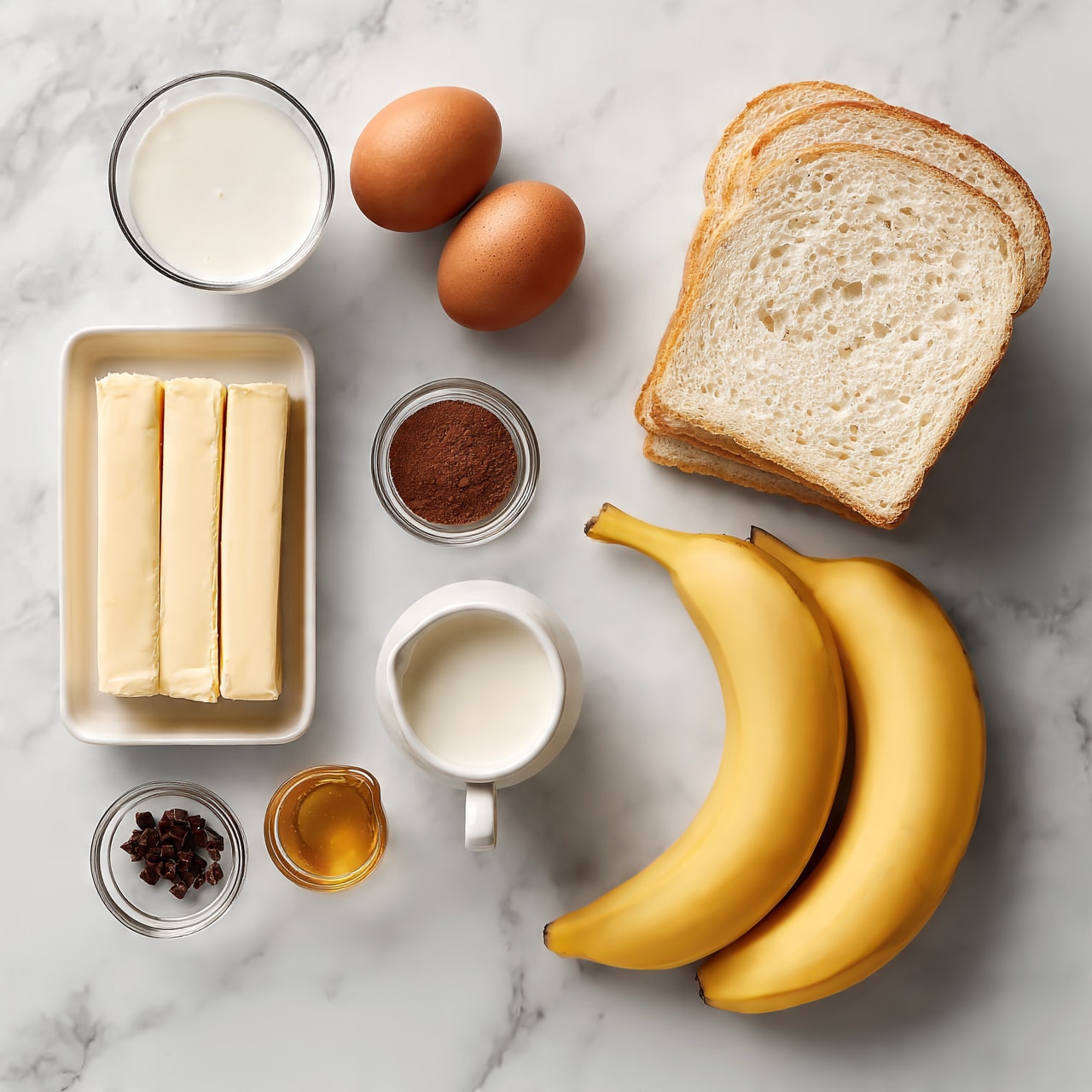 square image The image shows a white marble surface with ingredients neatly arranged. On the right is a stack of white bread slices, slightly leaning. Below the bread are two ripe yellow bananas lying side by side. To the left of the bananas, there is a small white pitcher filled with milk. Above the pitcher, a glass of white cream is placed. Further left, a rectangular white dish holds three sticks of butter. Above the butter, there are two brown eggs, with one slightly behind the other. Next to the eggs is a very small round glass bowl filled with a dark brown powder, likely cinnamon. Below the bowl is a tiny glass container with a small amount of golden honey. Near it is a small clear bowl with small dark chopped pieces, possibly nuts or chocolate. All items are carefully spaced on the white marble, creating a tidy and balanced layout. Photo taken with an iphone --ar 4:5 --v 7