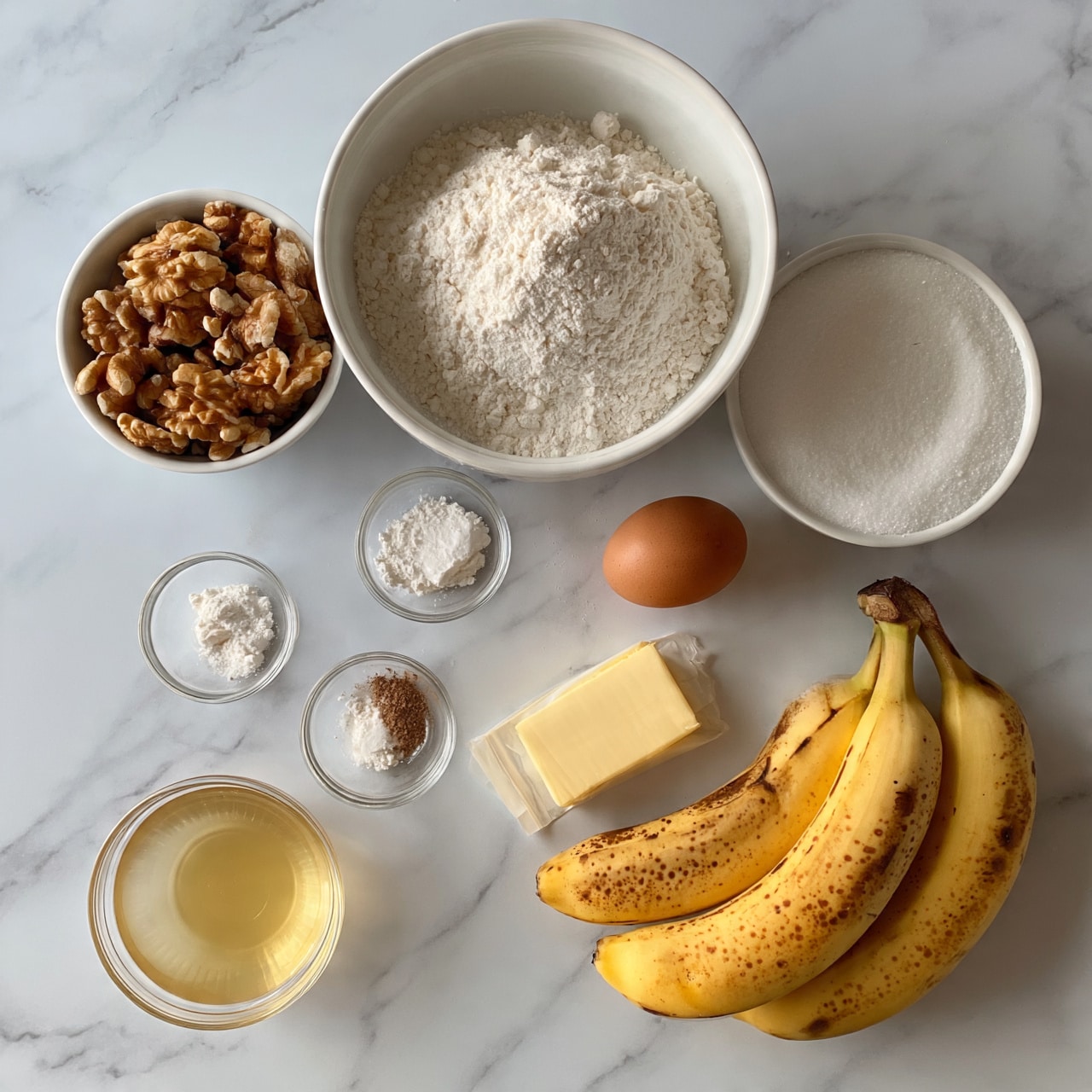 square image A white marbled surface holds several ingredients arranged neatly: three ripe bananas with brown spots lie at the bottom right, next to a small stick of light yellow butter wrapped in paper. Above the butter, there is one brown egg. A large white bowl full of white flour is placed at the top center, with a smaller white bowl of walnut halves to its left. To the right of the flour bowl is another white bowl filled with white granulated sugar. Below these are several small clear glass bowls with various white powders and a small amount of brown powder, and a small glass bowl of light golden honey is placed at the bottom left. Photo taken with an iphone --ar 4:5 --v 7