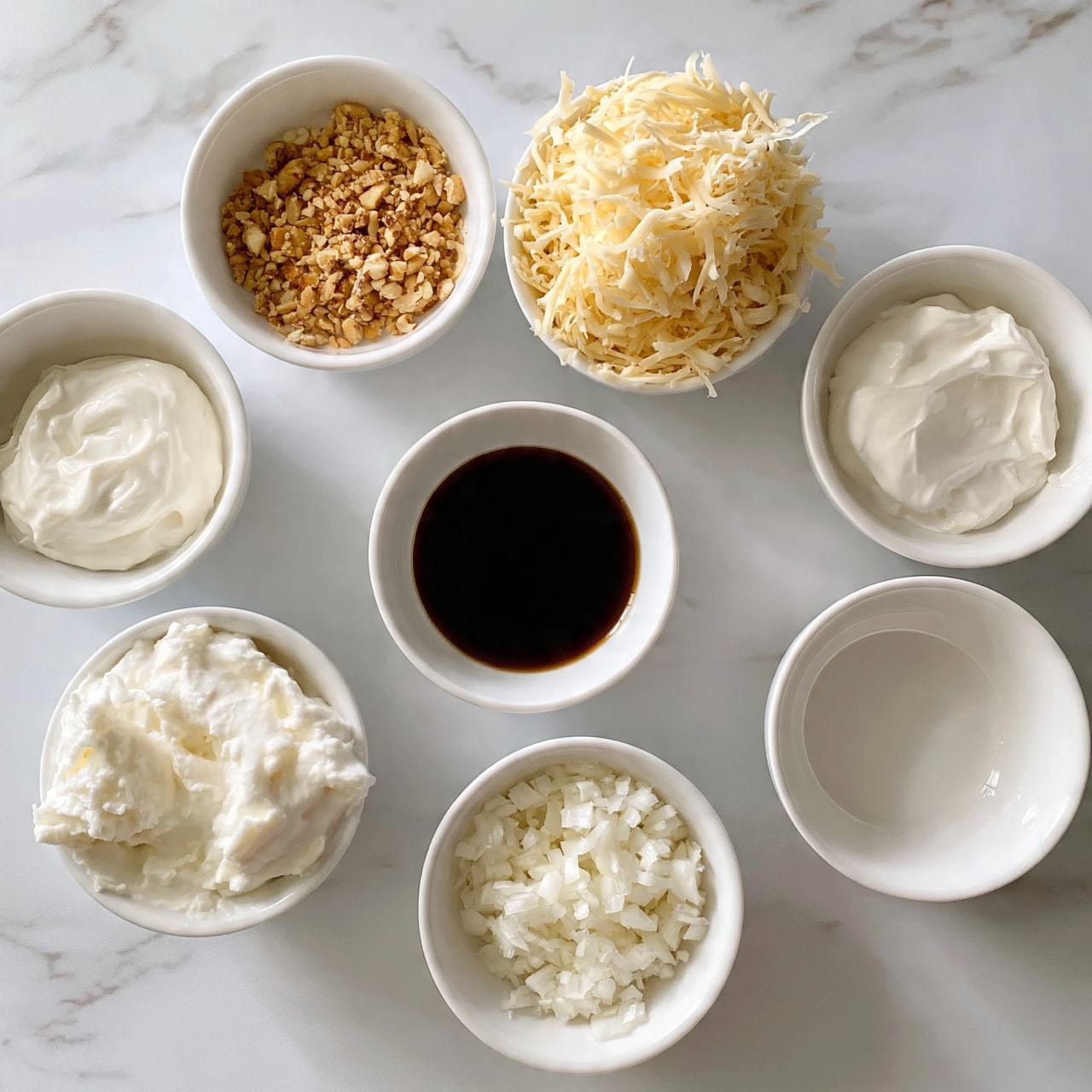 square image The image shows seven small white bowls arranged on a white marbled surface. Each bowl contains a different ingredient: one has light brown crushed nuts with a crunchy texture, another has shredded pale yellow cheese piled high, a third is filled with smooth white cream, the fourth holds dark brown soy sauce with a glossy surface, the fifth has a white thick creamy mix with soft texture, the sixth contains finely chopped white onions, and the last bowl is empty, showing its smooth white interior. The arrangement is neat and spaced evenly, and the lighting is bright, making the colors and textures clear. Photo taken with an iphone --ar 4:5 --v 7
