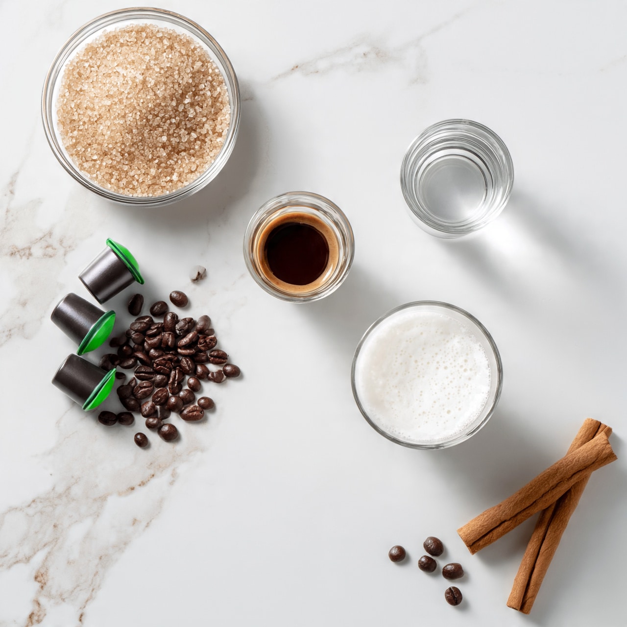 square image The image shows several coffee-making ingredients and items spread on a white marbled surface. At the top left, there is a clear glass bowl filled with light brown sugar crystals. Below and to the left, there are three dark coffee capsules with green tips, arranged next to scattered dark brown roasted coffee beans. In the center, a small clear glass contains a dark brown liquid, likely espresso. To the right, near the top, is a short clear glass of water. Below the espresso cup, there's a larger clear glass filled with white frothed milk. On the bottom right corner, two cinnamon sticks rest on the surface alongside a few scattered coffee beans. The photo taken with an iphone --ar 4:5 --v 7