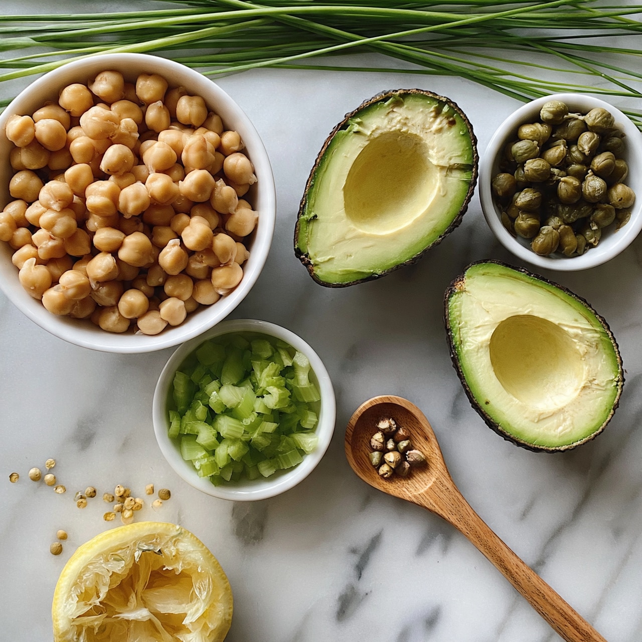 square image The image shows a white bowl filled with light brown chickpeas on the top left. To the right, two halves of avocados with dark green skin and light green flesh are placed on a white marbled surface. Next to them is a small white bowl with green capers. Below the chickpeas is a small white bowl with green chopped celery. A wooden spoon lies nearby, holding some small seeds or nuts. To the bottom left, there is a half lemon with yellow flesh and a small pile of seeds near it. Green chives spread across the top of the image. The photo taken with an iphone --ar 4:5 --v 7
