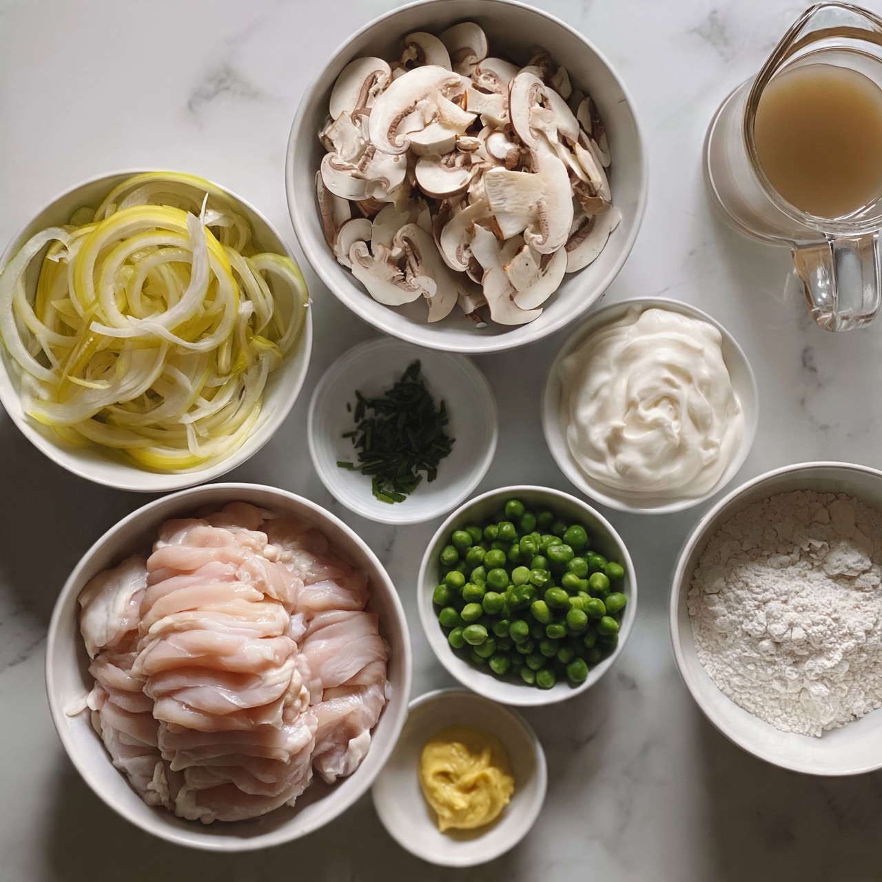 square image A top view of several white bowls placed on a white marbled surface, each holding different raw cooking ingredients arranged neatly; one large bowl with layered, light pink raw chicken pieces in close clusters, next to it a bowl filled with thin, pale yellow and light green sliced onion rings piled loosely, and another larger bowl with many sliced mushrooms showing their creamy white texture and brown edges scattered; a small bowl has thick white creamy sauce swirled, beside it a slightly bigger bowl with a small pile of chopped dark green chives; another bowl contains bright green peas heaped, and near it a white bowl filled with white flour; a clear glass jug holds a light brown liquid, and another tiny bowl has a dollop of smooth yellow paste; the whole setup looks clean and ready for cooking photo taken with an iphone --ar 4:5 --v 7