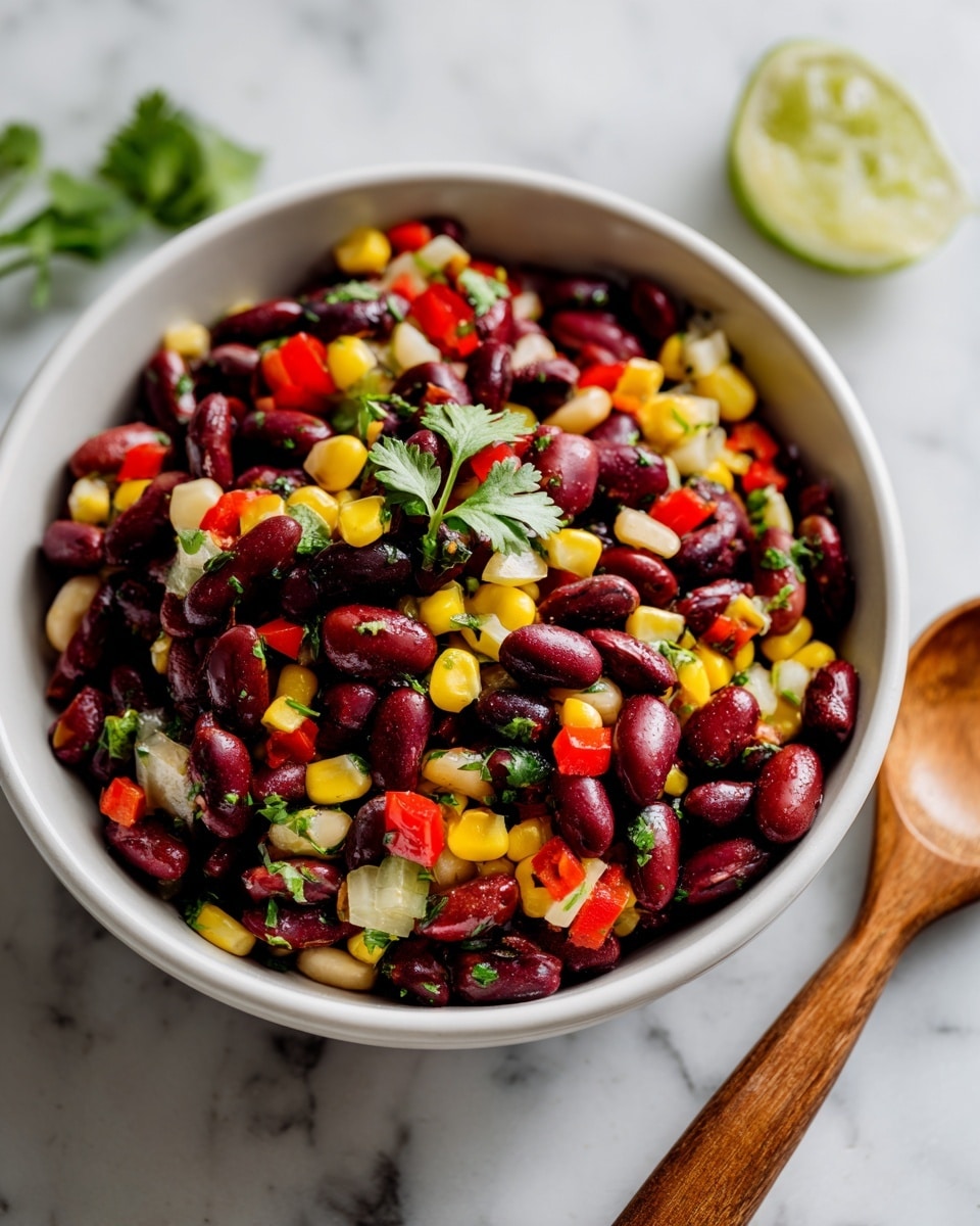 A white bowl filled with a colorful mix of three layers of beans—dark red kidney beans, black beans, and bright yellow corn kernels—combined with chopped red bell peppers and green herbs scattered throughout. The beans are shiny and plump, giving a fresh and juicy look. Fresh cilantro leaves are placed on top for garnish. The bowl sits on a white marbled surface with a wooden spoon and a slice of lime nearby, hinting at freshness and zest. photo taken with an iphone --ar 4:5 --v 7