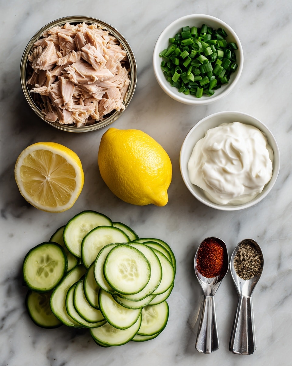 The image shows an open can of light brown tuna with a slightly flaky texture at the top left. Below the tuna, there are two piles of sliced cucumber rounds with a pale green inside and a darker green skin, neatly stacked in layers. To the right of the cucumbers, there is a whole bright yellow lemon placed in the center. Above the lemon, a small white bowl holds chopped green chives, finely cut into small ring shapes. Next to the bowl of chives, another white bowl contains thick white sour cream with a smooth texture. On the far right, three metal measuring spoons are laid out horizontally, each with a different ingredient: deep red paprika powder in the largest spoon, coarse white salt in the middle spoon, and dark black pepper in the smallest spoon. All items are placed on a white marbled surface. Photo taken with an iphone --ar 4:5 --v 7