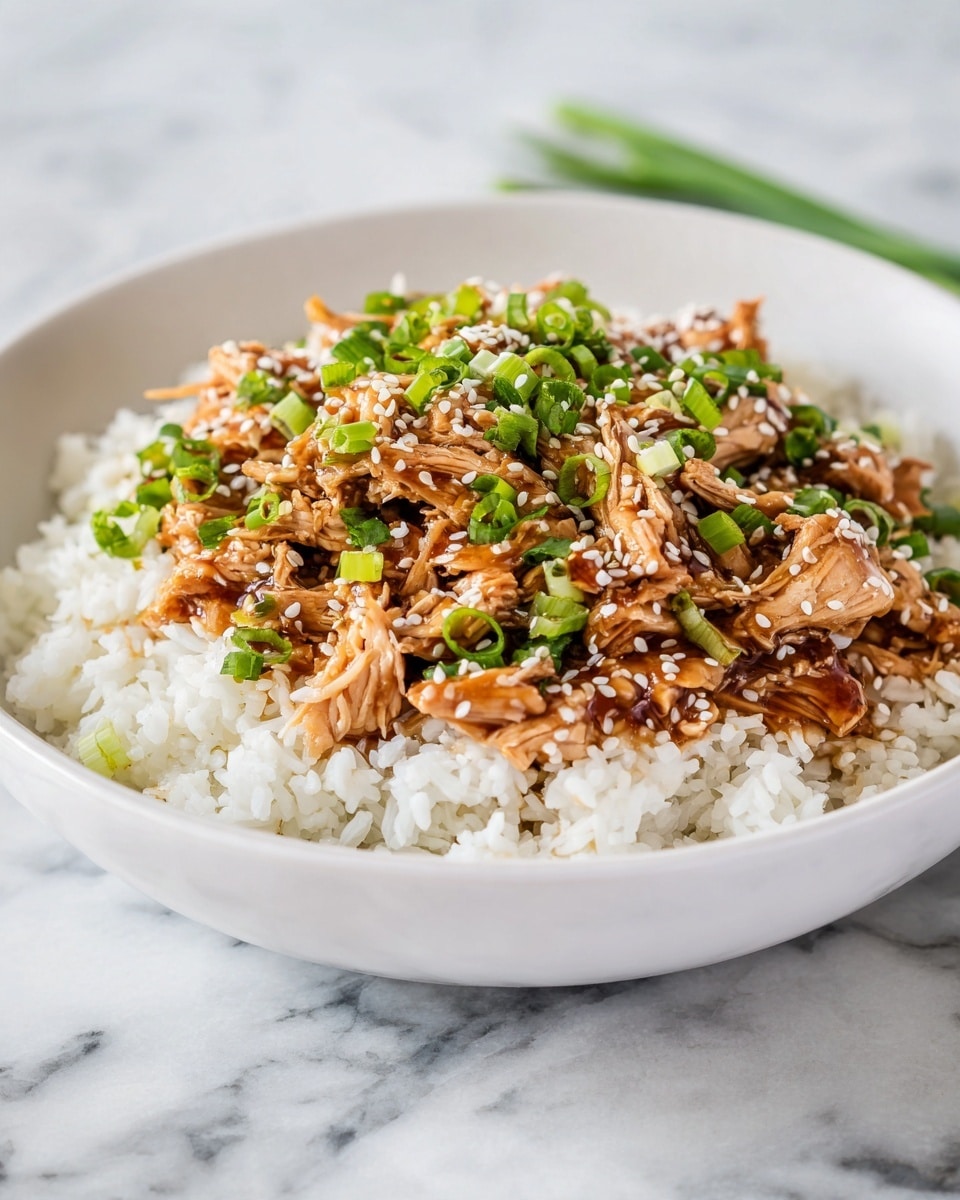 A white bowl filled with a base layer of plain white rice topped with a generous layer of shredded brown chicken pieces mixed with sauce. The chicken is garnished with small slices of bright green chopped scallions and sprinkled with white sesame seeds. The dish is placed on a surface with a white marbled texture, and there are some green scallions visible on the side. photo taken with an iphone --ar 4:5 --v 7