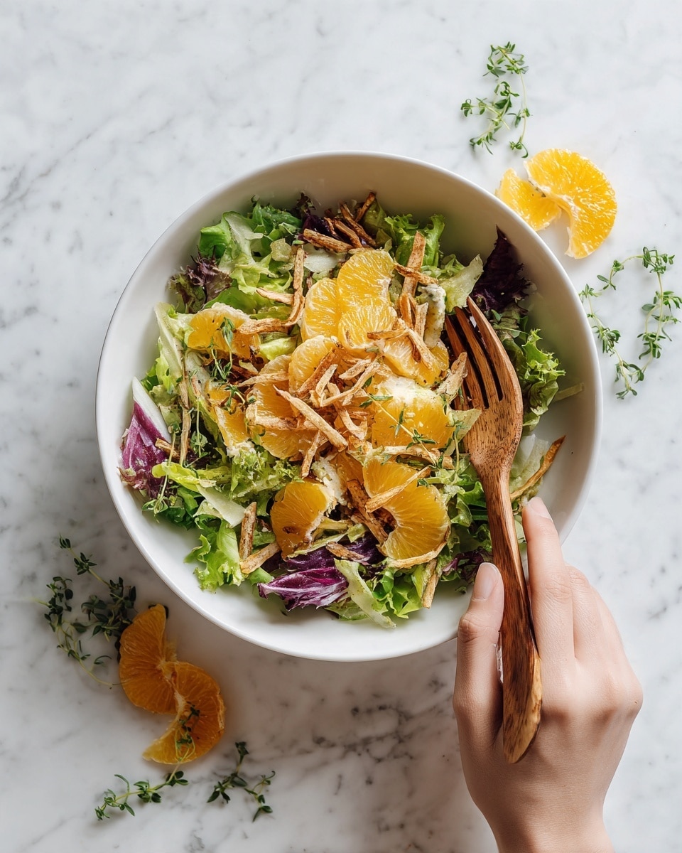 A white bowl filled with a fresh salad sits on a white marbled surface. The salad has three main layers: the bottom layer is mixed green lettuce leaves with some purple lettuce scattered throughout, the middle layer shows bright orange slices of what looks like mandarin or orange segments spread evenly, and the top layer has thin light brown crispy strips arranged across the salad, along with small pale yellow cheese shreds or slices. A woman's hand with light skin is holding a wooden fork near the bowl. Some orange slices and green herbs are placed around the bowl on the white marbled surface. photo taken with an iphone --ar 4:5 --v 7