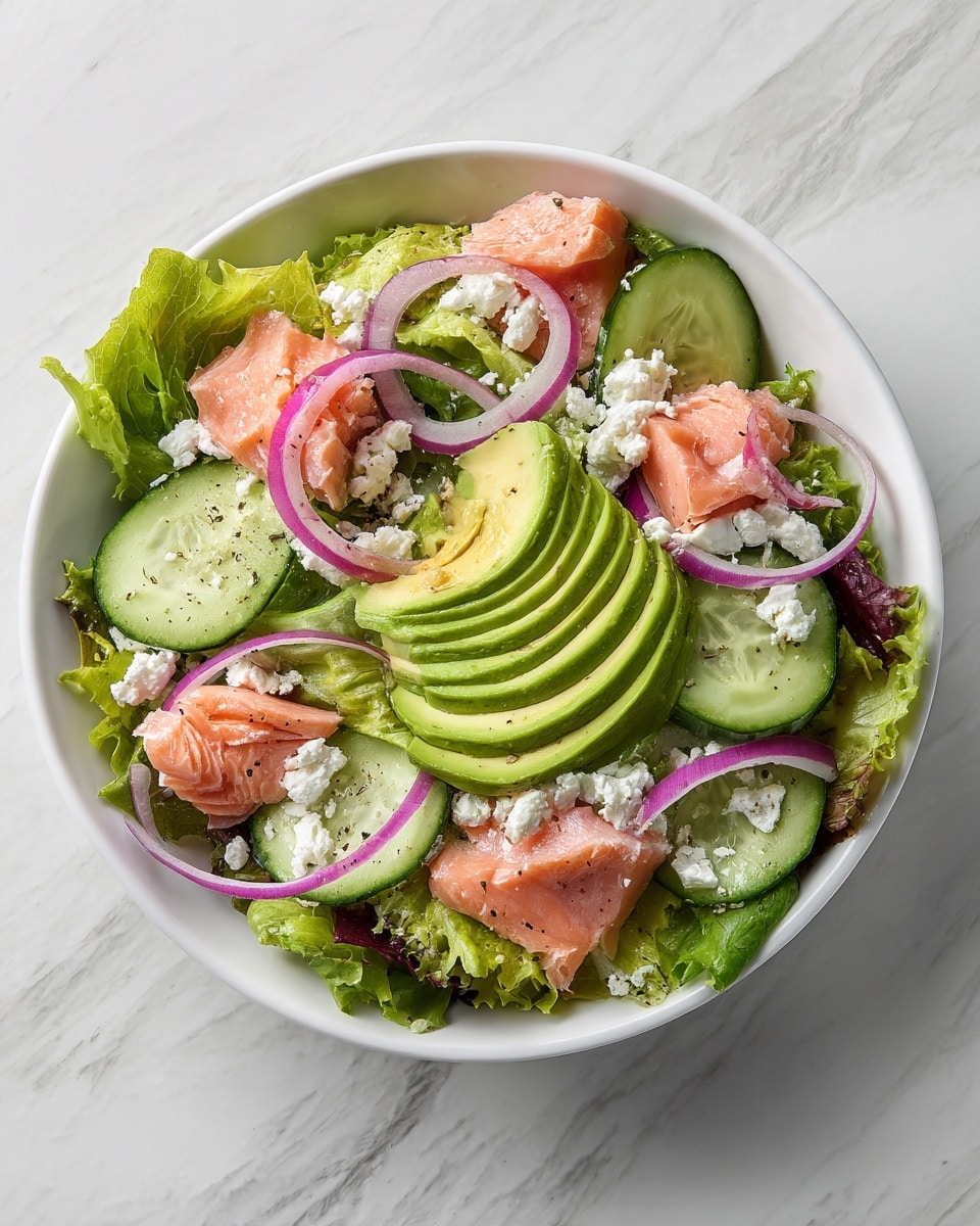 The image shows a fresh salad in a white bowl placed on a white marbled surface. The salad has several layers, starting with a base of green leafy lettuce. On top of this, there are slices of avocado arranged in a fan shape with smooth light green flesh. Pieces of cooked pink salmon are spread evenly across the salad. Thin rings of red onion add a touch of purple, and thin cucumber slices with dark green edges are scattered around. Small white crumbles of cheese are sprinkled over everything. The textures range from soft salmon and avocado to crunchy lettuce and onions. Photo taken with an iphone --ar 4:5 --v 7