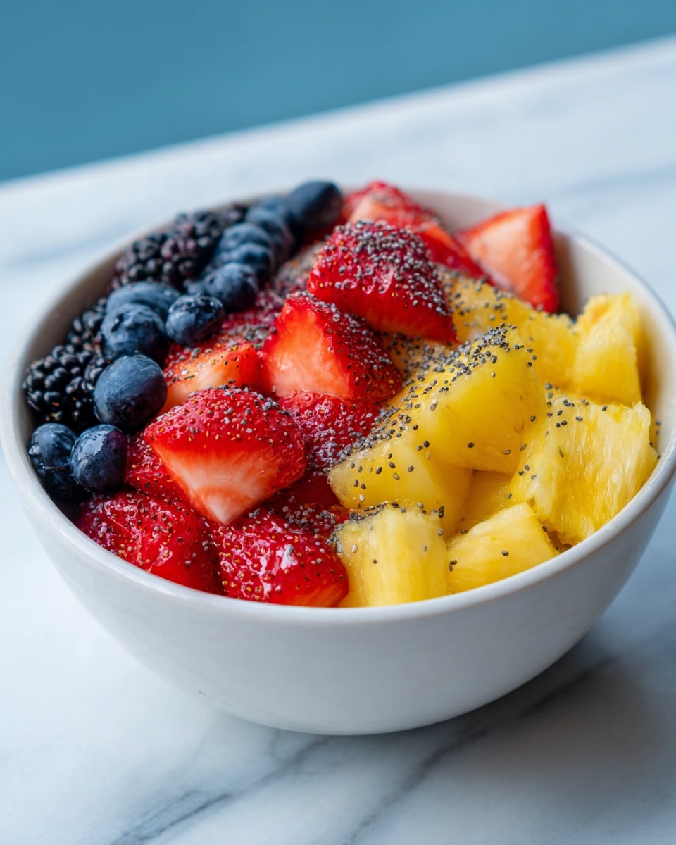 A white bowl filled with a colorful mix of fresh fruit pieces shows three main layers: the bottom layer has bright yellow pineapple chunks with a juicy texture, the middle layer has deep red, cut strawberries with a soft look, and the top layer is covered with small blue blueberries and black blackberries. Tiny black seeds are sprinkled evenly over all the fruit, adding small specks of texture. The bowl sits on a white marbled surface with a soft blue background visible. Photo taken with an iphone --ar 4:5 --v 7